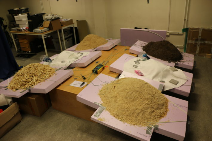 En bild av hur olika täckmaterial, som sågspån och dukar, testas för snölagring.