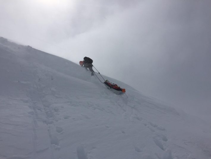 Peter kämpar sig upp för ravinen med pulkan hängandes bakom.
