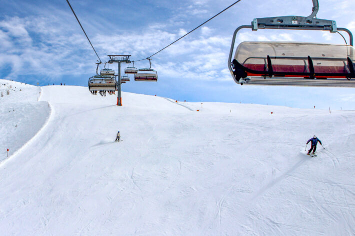 Två ensamma skidåkare i stor bred pist i St Jakob, fotat från sittliften.