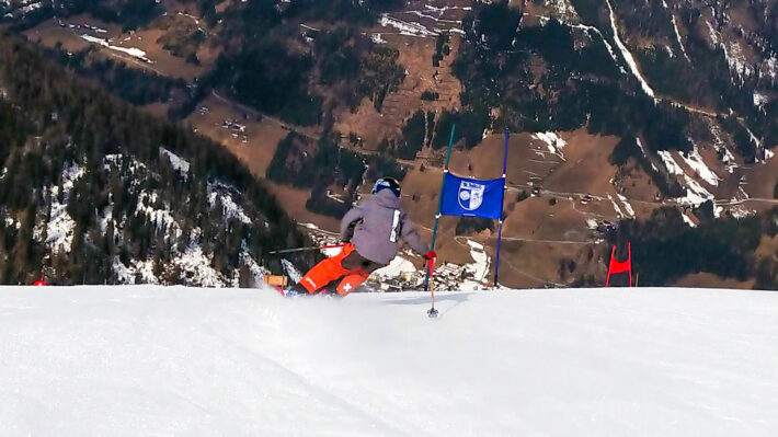 Aron Rimfors i storslalombana på vit pist i stark kontrast till grönbrun dalgång i St Jakob in Defereggen.