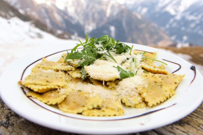 Grönsaksravioli med parmesanost och balsamicovinäger med suddiga alper i fonden.