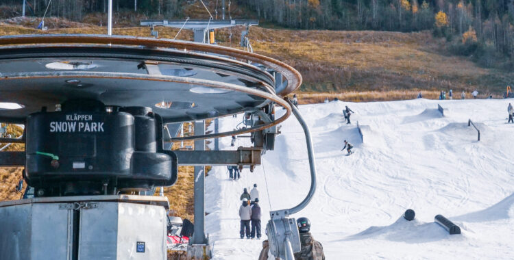 Den ikoniska liften i Kläppen Snowpark med stor kontrast mellan snö och gräs.