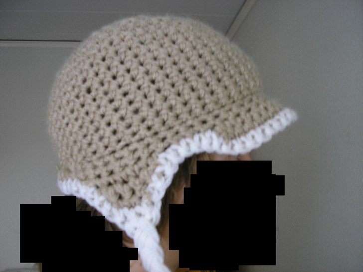 Kakifärgad mössa med earflaps, flätor och skär. Foto: Sandgren. Åkare: Sandgren.