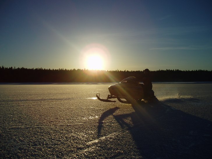 Testar ny skoter på isen utanför stugan, Solen i. Foto: Olov Nyström. Åkare: Arvid Nyström.