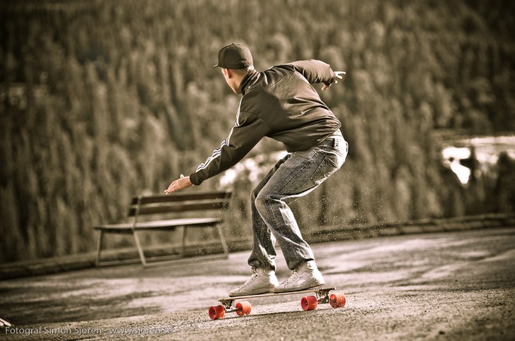 Lite longboard på blöt asfalt kan ge sköna spru. Foto: Simon Sjörén www.sjoren.se. Åkare: Jonatan Axberg.